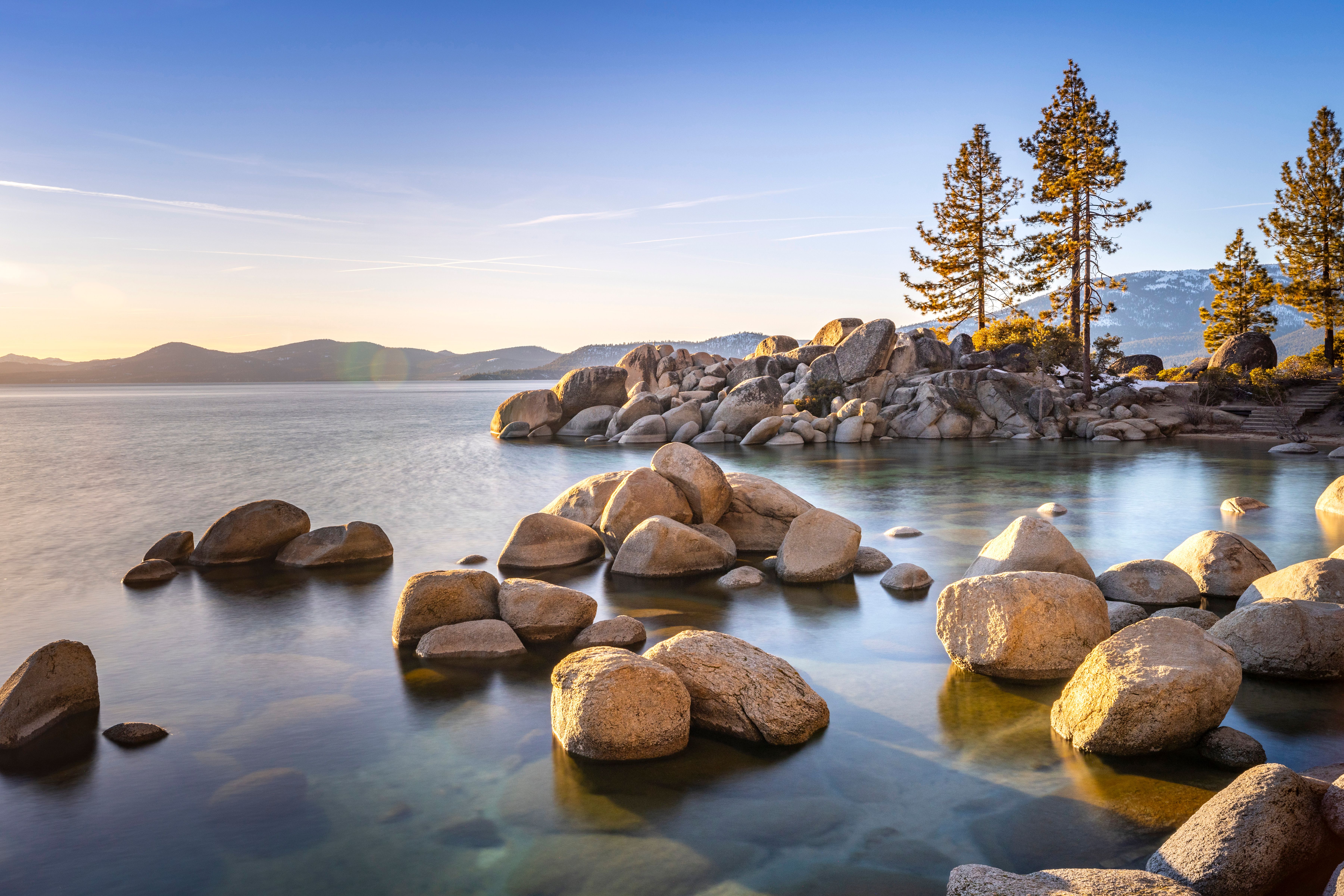 Golden evening light on the Lake Tahoe shoreline, with smooth stones and still water